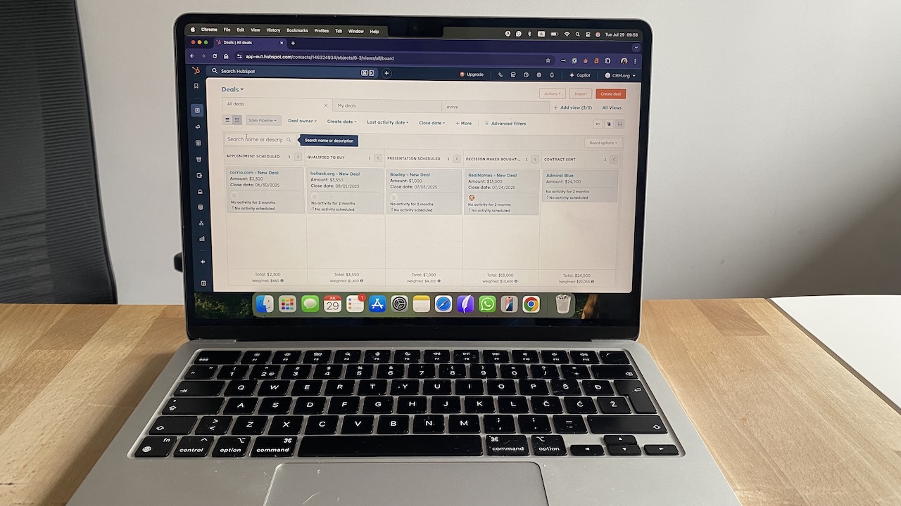 Laptop screen with HubSpot CRM deals pipeline, displaying sales opportunities organized by stage and deal amount.