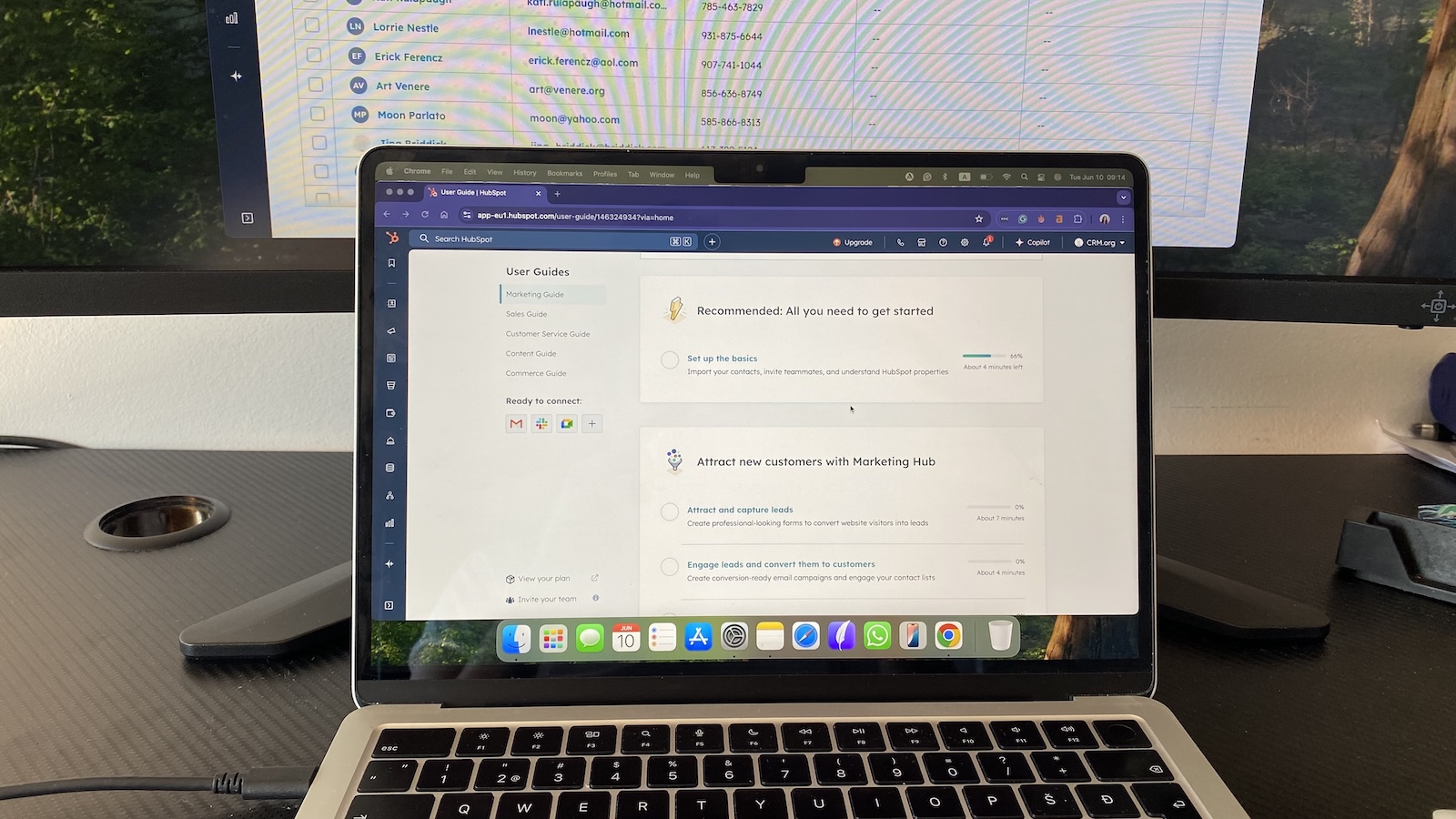 Laptop showing HubSpot onboarding dashboard with user guides, setup tasks, and marketing hub options.
