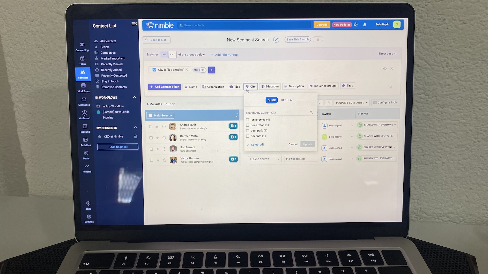 A MacBook laptop displaying Nimble CRM’s contact segmentation interface, with filters applied to city and organization fields, and a list of matching contacts.