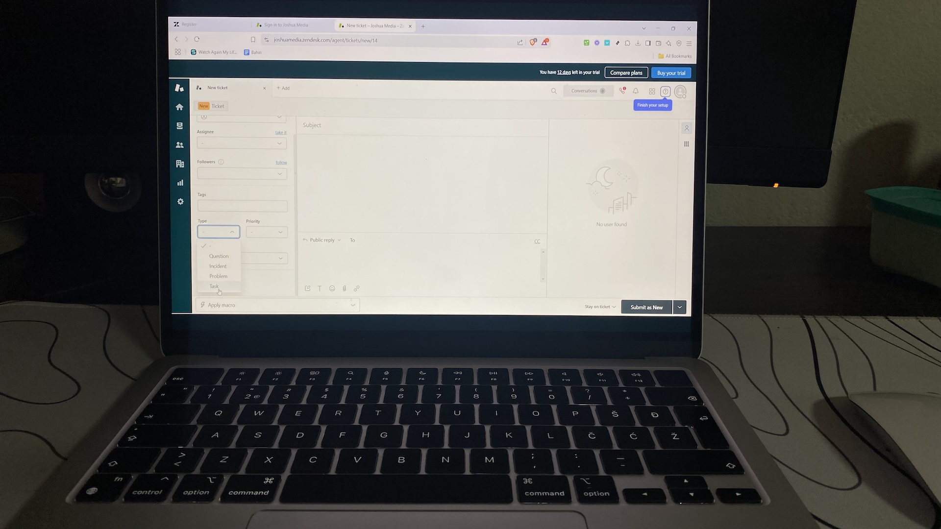 Laptop screen with Zendesk new ticket form open, showing fields for assignee, priority, tags, and reply options.