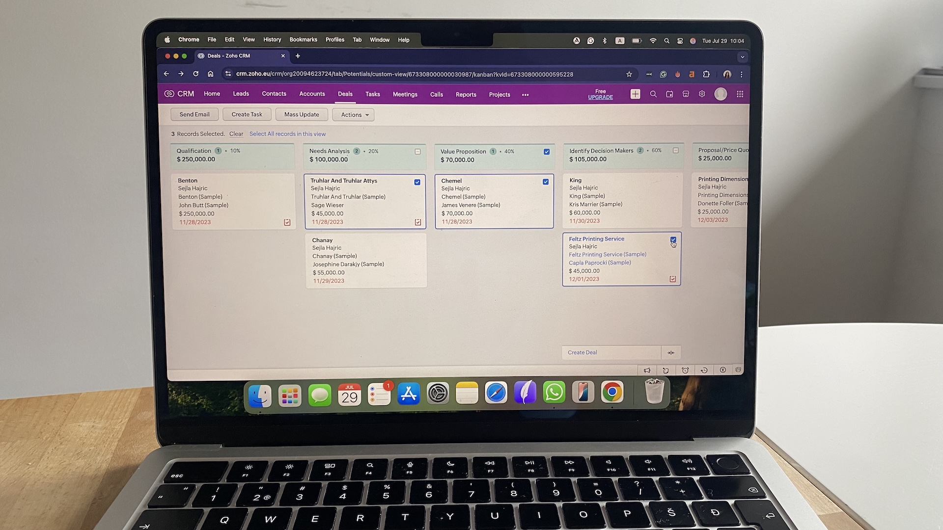 Zoho CRM deals board on laptop showing multiple sales stages including qualification, needs analysis, and value proposition.