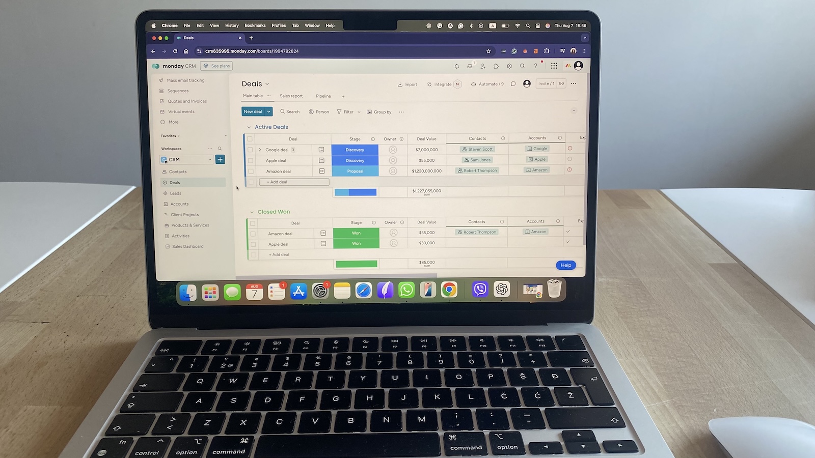 Laptop showing Monday CRM deals board with active and closed deals, including deal names, sales stages, owners, values, and linked contacts and accounts.